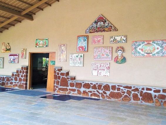 The entrance to the Zapurza Museum of Art & Culture, featuring a colorful wall decorated with various artworks and artifacts. A vintage cannon is parked nearby.